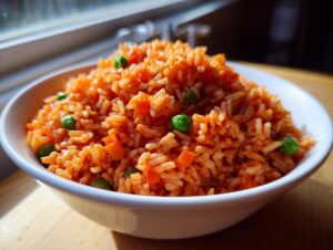 A white bowl filled high with vibrant orange spanish rice mixed with bright green peas and diced carrots.
