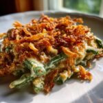 A close-up serving of amazing green bean casserole topped generously with crispy fried onions.