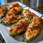 Close-up of baked jalapeño poppers stuffed with cheese and topped with a golden, crispy breadcrumb crust.