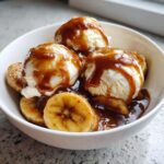 Close-up of Bananas Foster featuring caramelized bananas, vanilla ice cream scoops, and rich caramel sauce.
