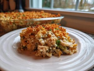 A serving of creamy chicken and wild rice casserole with a golden, crunchy topping on a white plate.