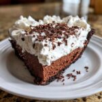 A decadent slice of Christmas chocolate cream pie featuring rich chocolate filling, whipped cream topping, and chocolate shavings.