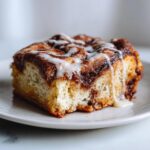 Close-up of a square slice of Cinnamon roll casserole, rich with cinnamon swirl and drizzled with white vanilla icing.