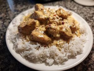 Close-up of creamy sauce-covered chicken pieces served over fluffy white rice, a perfect chicken and rice meal.