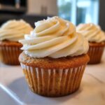Close-up of a fluffy vanilla cupcake topped with a swirl of creamy white vanilla frosting.