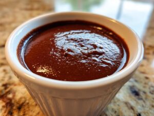 Close-up of rich, dark homemade chocolate pudding filling a white, fluted ramekin.
