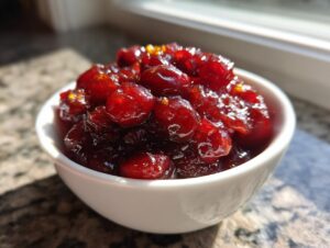 Close-up of chunky, glistening homemade cranberry sauce served in a small white bowl.