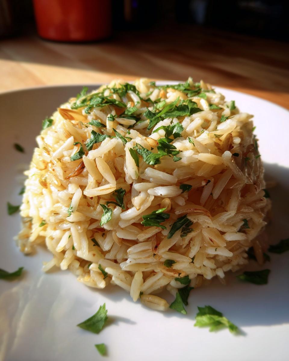 A mound of golden brown rice pilaf topped with fresh chopped parsley, served on a white plate.