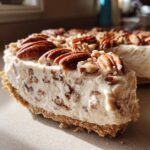 Close-up of a thick slice of Pecan cream pie showing the creamy filling mixed with chopped pecans and topped with whole pecans.