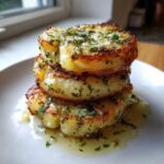 Three golden-brown potato stacks stacked high, drizzled with melted garlic herb butter and parsley.