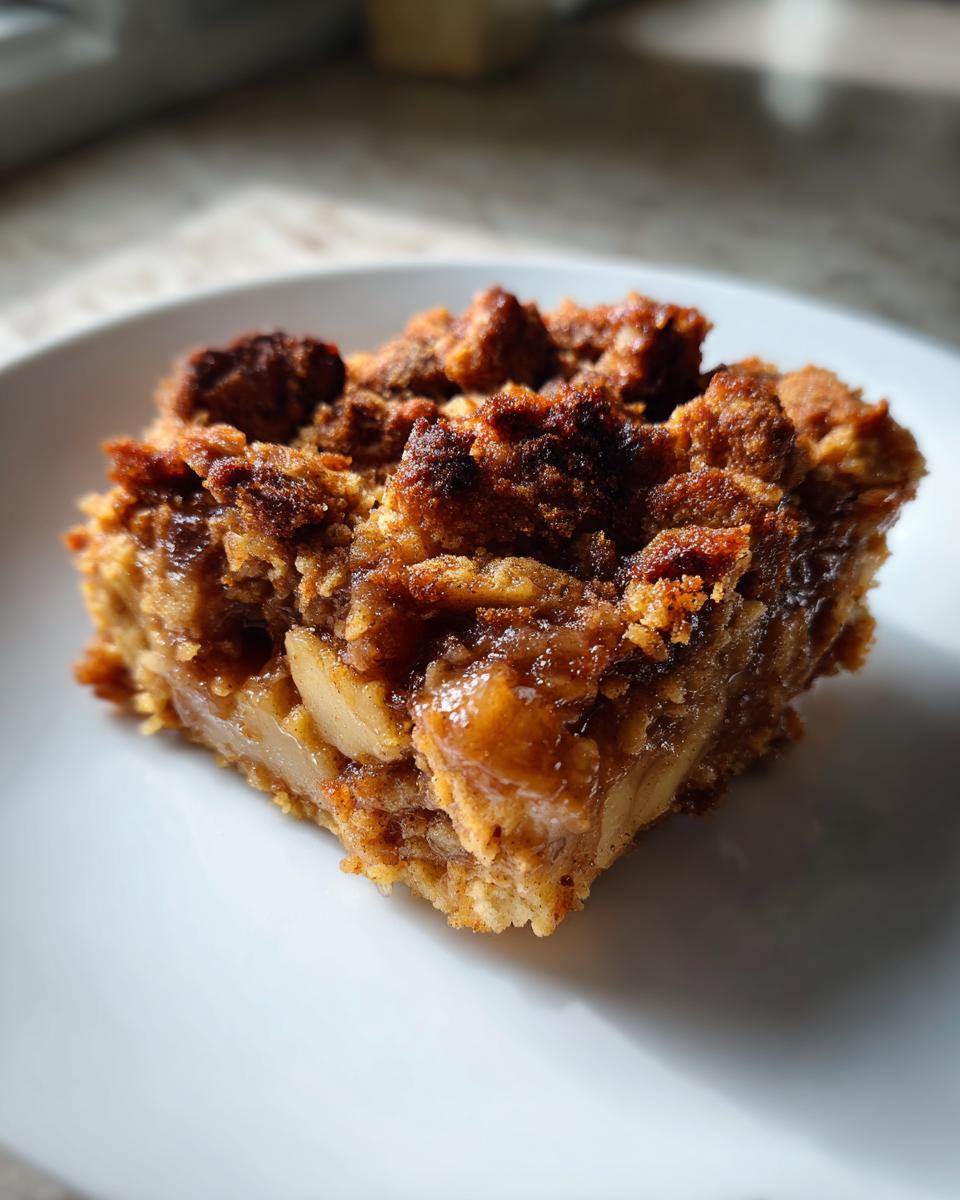 Close-up of a square slice of warm apple pie dump cake with a crumbly, caramelized topping.