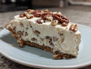 Close-up of a thick slice of Pecan cream pie with a creamy white filling studded with pecans on a light blue plate.