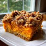 A square slice of vibrant orange southern sweet potato casserole topped with a crunchy pecan streusel.