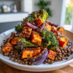 A vibrant veggie lentil salad featuring roasted sweet potatoes, charred broccoli florets, and red onion served over brown lentils.