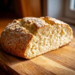 Close-up of a rustic loaf of freshly baked soda bread, cut to show the soft interior texture.