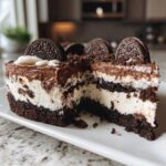 A cross-section view of a rich, four-layer dirt cake showing chocolate crust, creamy filling, and pudding, topped with Oreos.