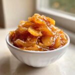 Close-up of glossy, spiced apple pie filling recipe piled high in a small white bowl.