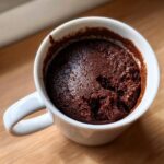 Close-up of a rich, dark chocolate Cottage Cheese Microwave Brownie baked inside a white mug.