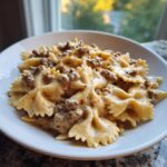 A close-up of creamy beef pasta made with farfalle (bowtie) noodles in a white bowl.
