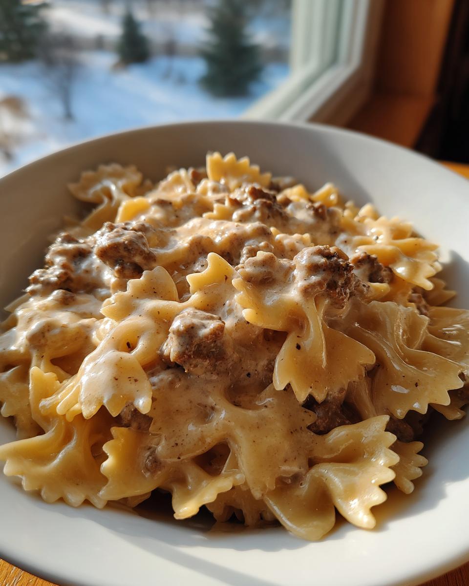 Close-up of creamy beef pasta made with farfalle (bowtie) noodles in a white bowl.