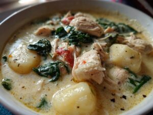 Close-up of creamy chicken gnocchi soup featuring tender chicken pieces, spinach, and potato gnocchi in a rich broth.