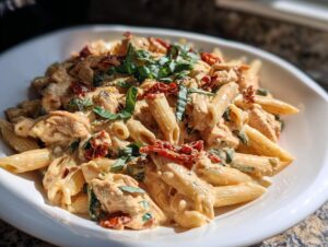Close-up of creamy Marry Me Chicken Pasta with sun-dried tomatoes and fresh basil garnish.