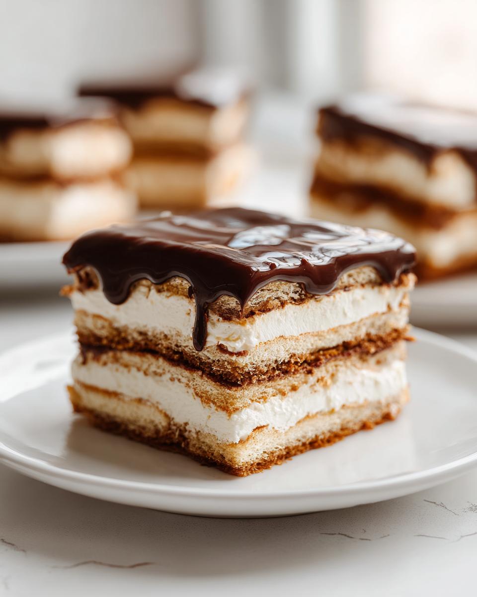 A decadent slice of eclair cake featuring layers of pastry, cream filling, and dripping chocolate ganache on a white plate.