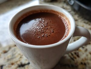 Close-up of a rich, dark french hot chocolate with small bubbles on the surface, served in a white mug.
