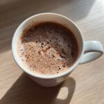 Close-up of a white mug filled with freshly made hot cocoa mix, showing a rich, foamy top layer.
