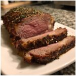 Close-up of a perfectly cooked prime rib recipe roast, sliced to show medium-rare center and herb crust.