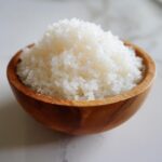 Close-up of perfectly cooked and seasoned sushi rice piled high in a small wooden bowl.