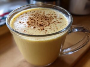 Close-up of a glass mug filled with creamy homemade eggnog, topped with a dusting of cinnamon.