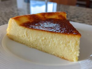 A perfect slice of silky egg custard with a deeply caramelized, glossy top, served on a white plate.