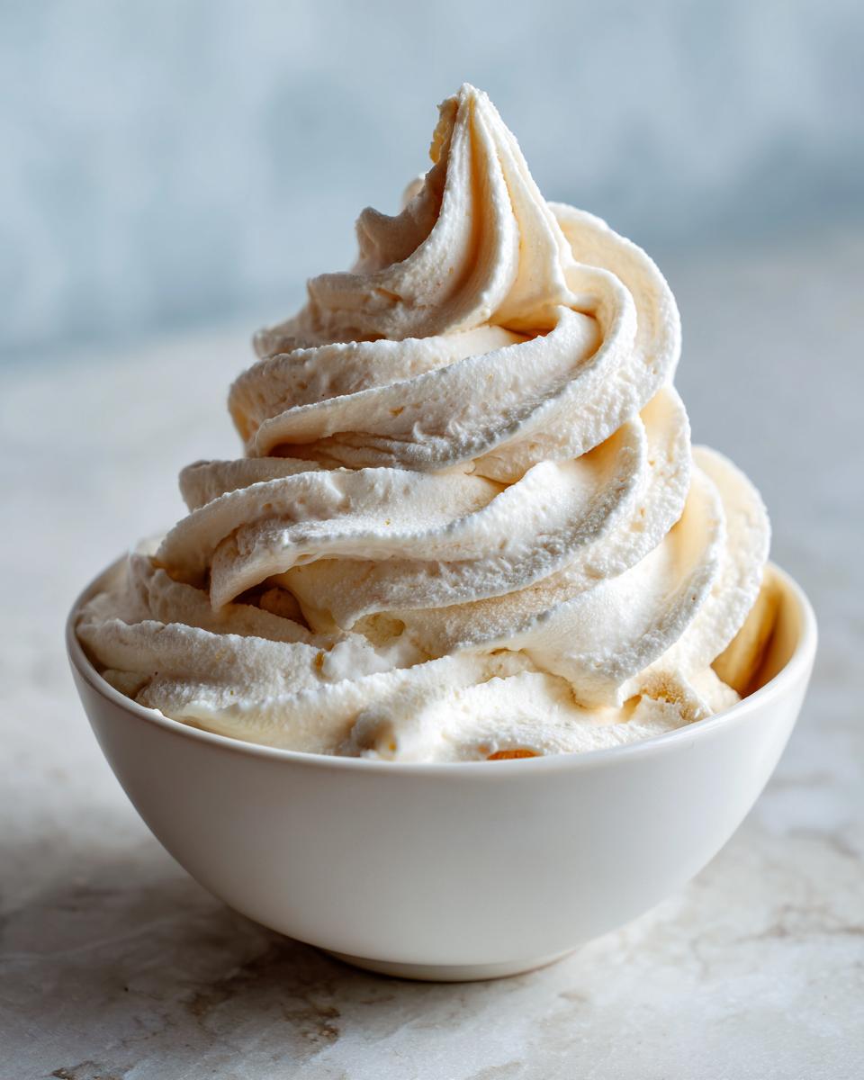 A perfect swirl of creamy, pale yellow banana ice cream served in a small white bowl.