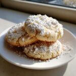 Three soft 3-ingredient butter cookies heavily dusted with powdered sugar, stacked on a white plate.