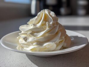 A beautifully piped swirl of creamy vanilla buttercream frosting sitting on a small white dish.