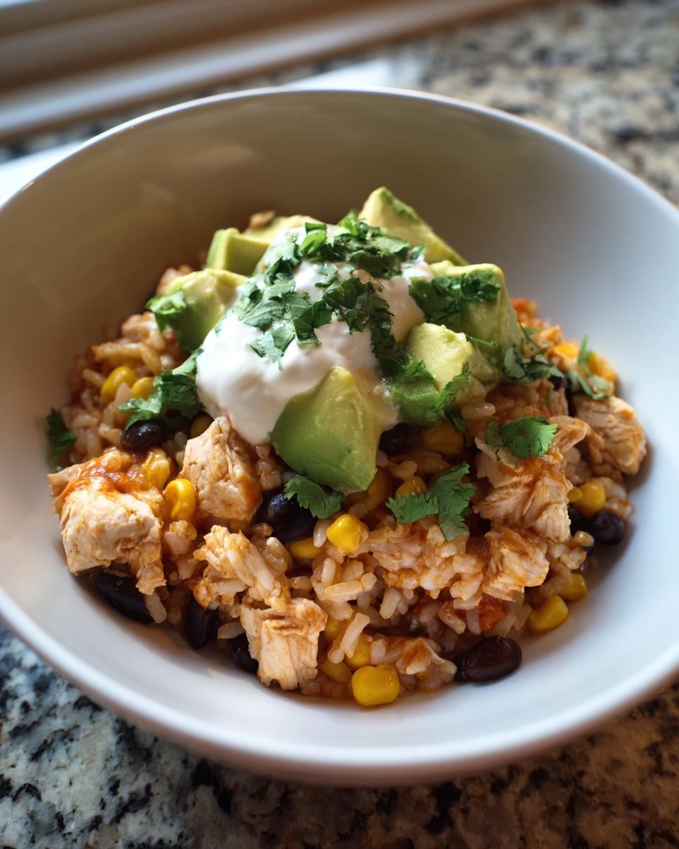 A close-up of a delicious chicken burrito bowl topped with avocado, sour cream, and cilantro.