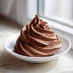 A beautiful swirl of rich, dark chocolate frosting piped onto a small white dish.