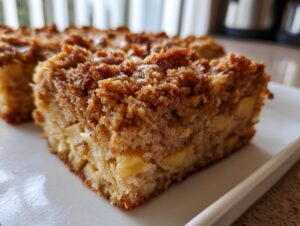 Close-up of a square slice of apple baked oatmeal featuring chunks of apple and a cinnamon streusel topping.