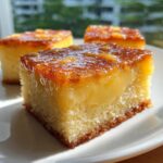 A close-up of a square slice of moist cassava cake with a thick, creamy custard layer and a shiny, caramelized topping.