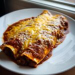 Two delicious cheese enchiladas smothered in rich red sauce and melted shredded cheese.