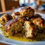 Close-up of golden-brown chicken piccata meatballs served in a bright lemon-butter sauce on a white plate.
