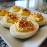 Close-up of several classic deviled eggs filled with creamy yolk mixture and sprinkled with paprika.
