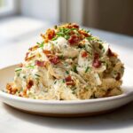 A mound of creamy honey mustard chicken salad topped generously with crispy bacon bits and fresh chives.