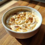 Close-up of a white bowl filled with creamy onion dip topped with caramelized onions.