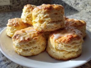 A stack of golden brown, fluffy scones topped with a thin white glaze, ready to eat.