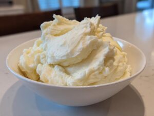 A generous serving of incredibly fluffy mashed potatoes piled high in a white bowl.