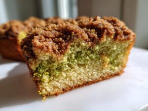 Close-up of a slice of moist pistachio coffee cake showing the green pistachio layer and rich brown streusel topping.