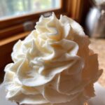 Close-up of perfectly piped, fluffy cream cheese frosting showing beautiful swirls and peaks.