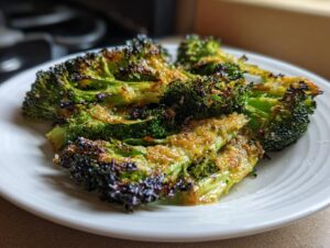 Close-up of crispy, charred, and cheesy smashed broccoli florets served on a white plate.